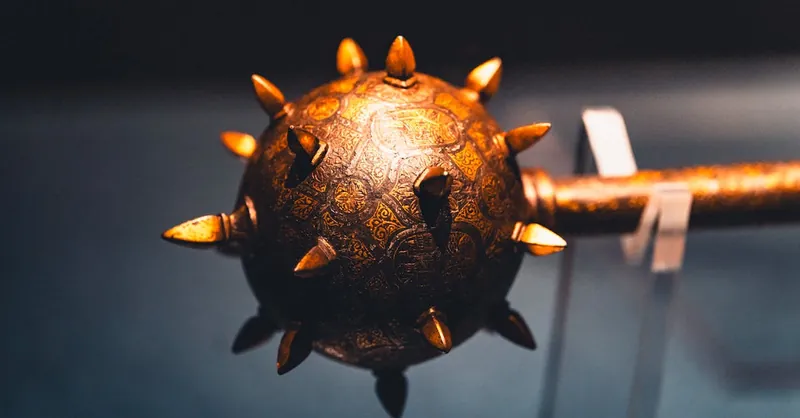 Detailed view of a medieval spiked mace with intricate engravings on display.