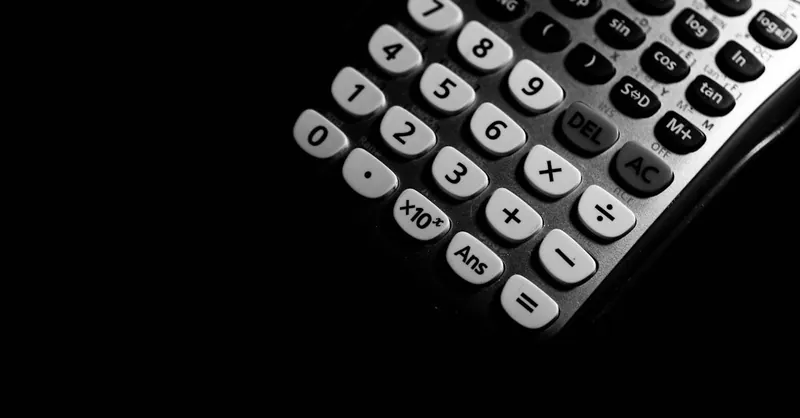 Detailed black and white photo of a calculator keypad highlighting numbers and functions.