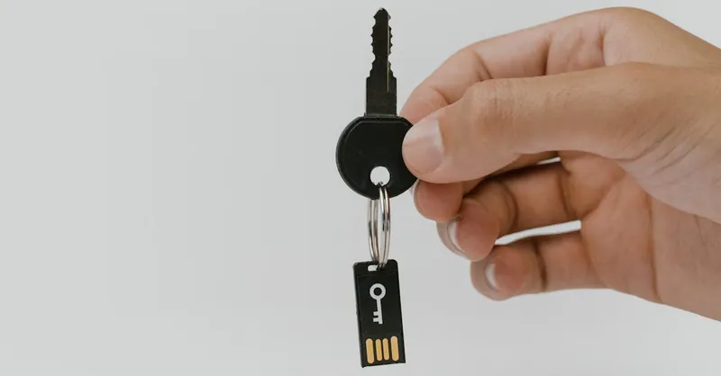A close-up of a hand holding a key with an attached USB drive, highlighting security and technology.
