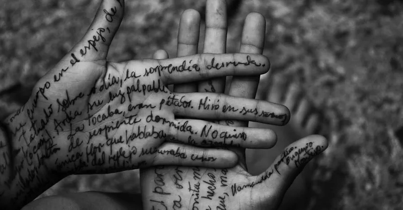 Artistic black and white photo of hands with handwritten text on skin.